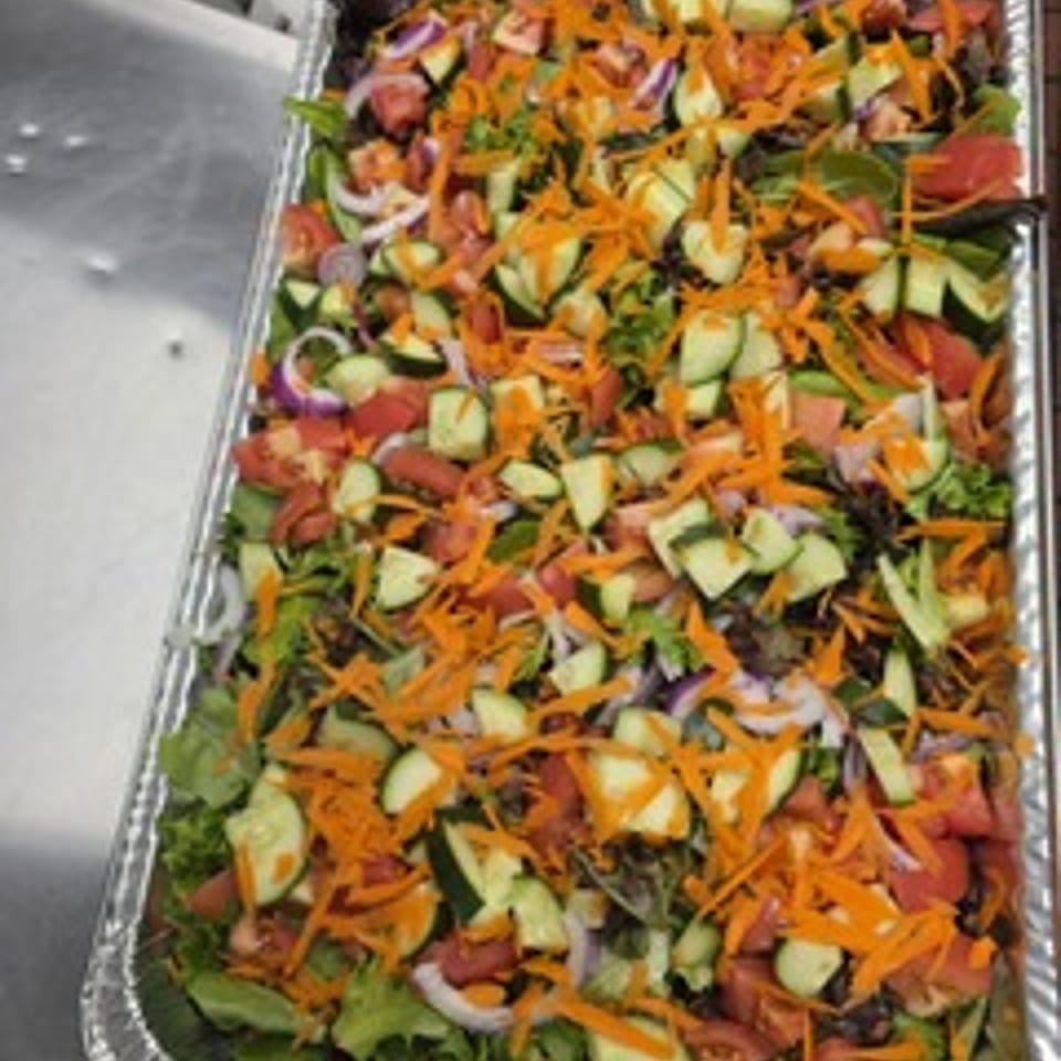 Sweet Fingers catering salad tray with mixed greens and sliced vegetables.